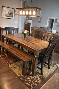 Dining room with wooden table, chairs, and bench on a patterned rug.